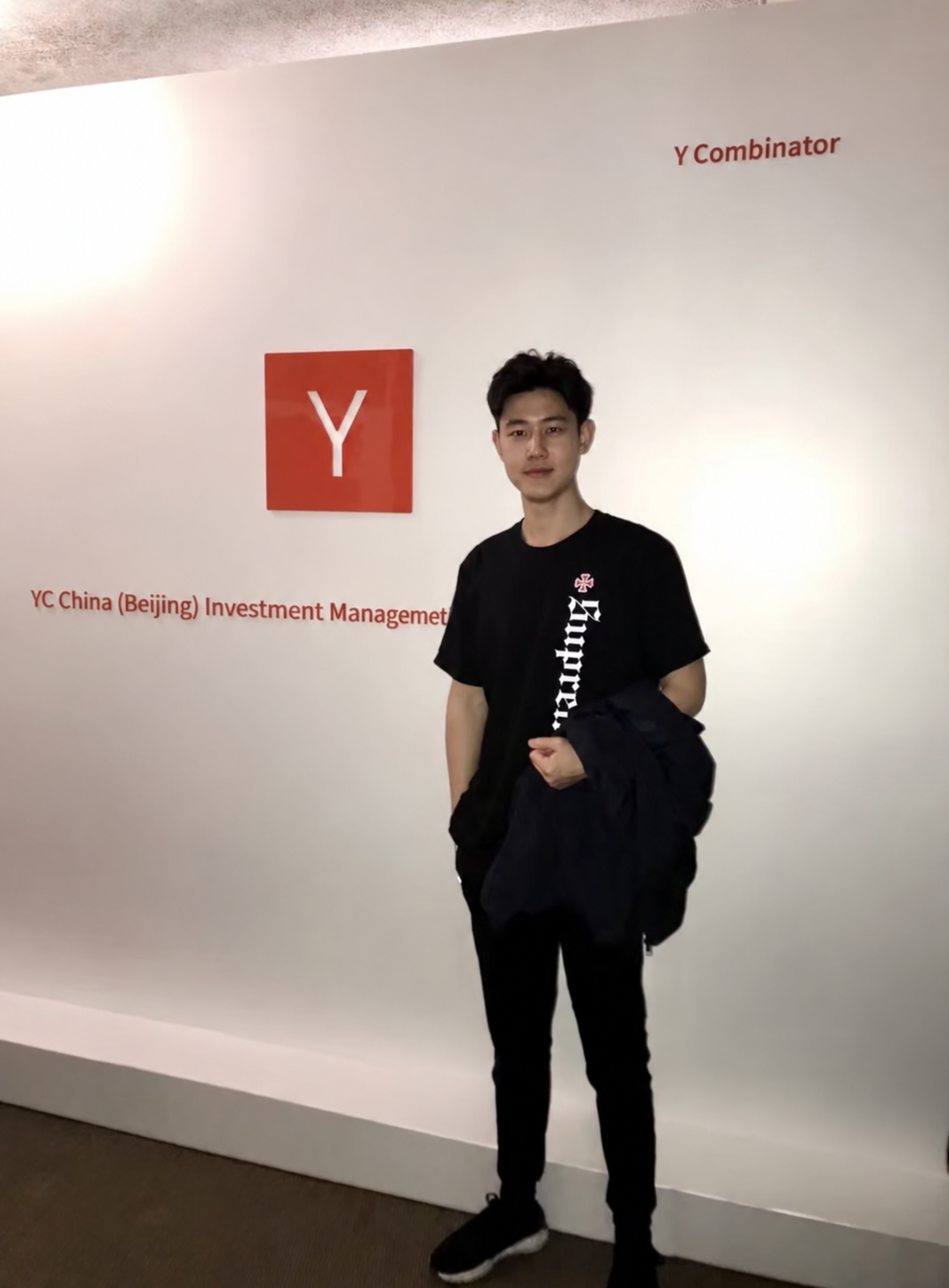 Kehan Dong standing in front of the YC China sign.