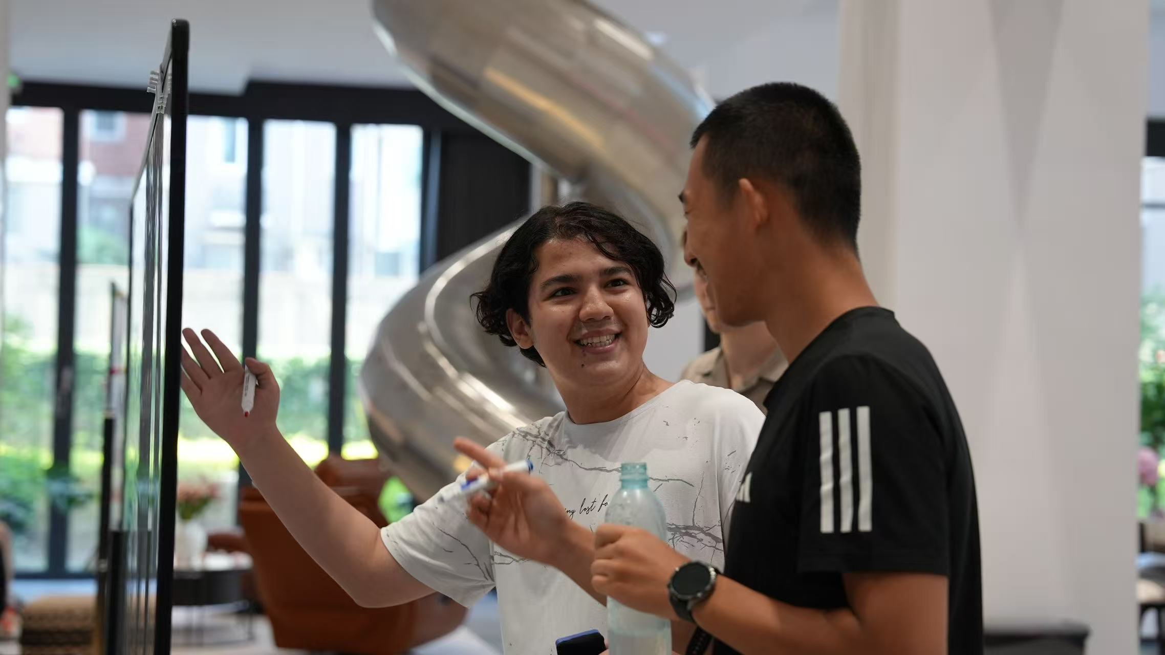 Two people exchanging ideas beside a whiteboard